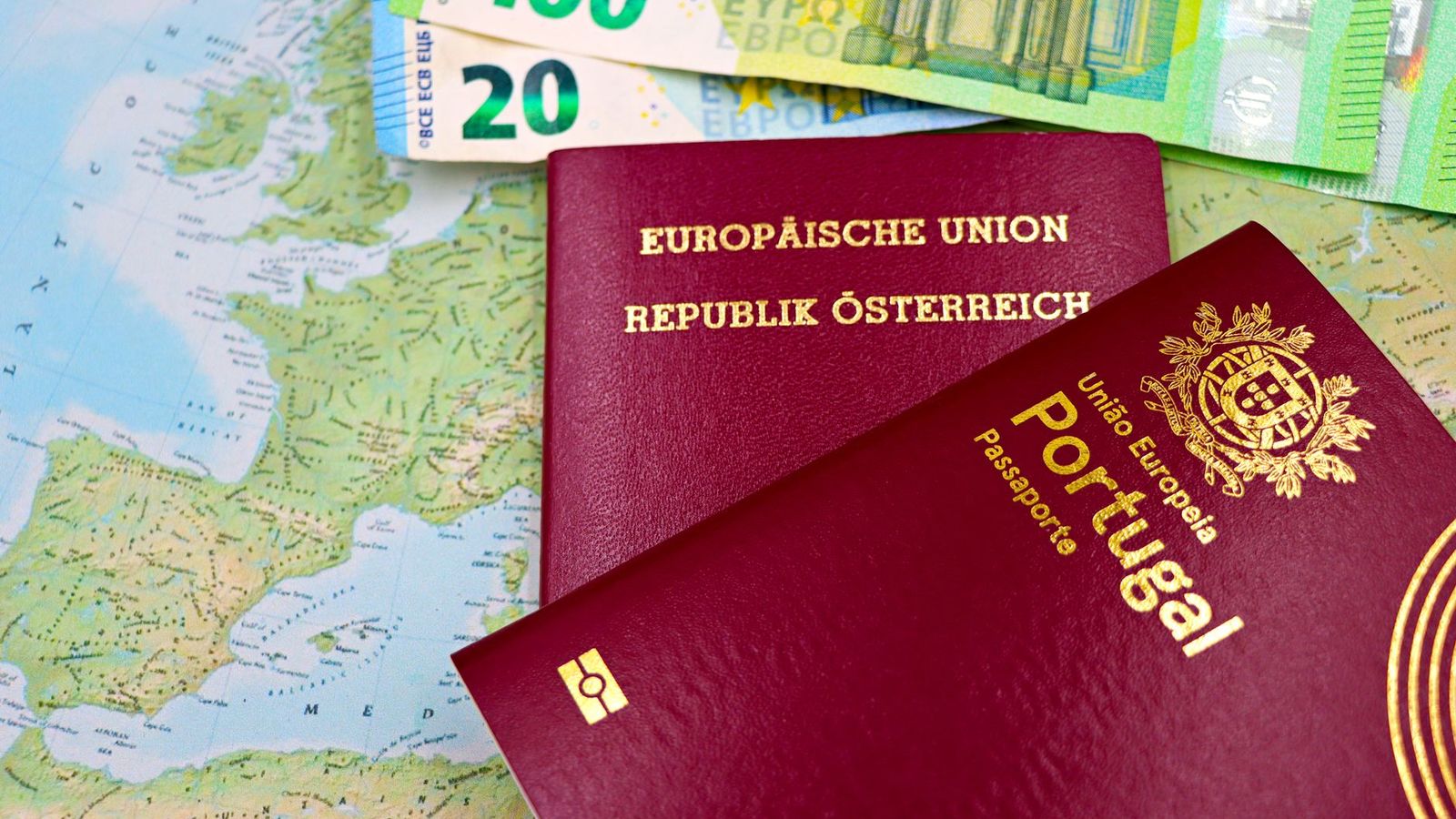 Deux passeports européens posés sur une carte, avec des billets en euros