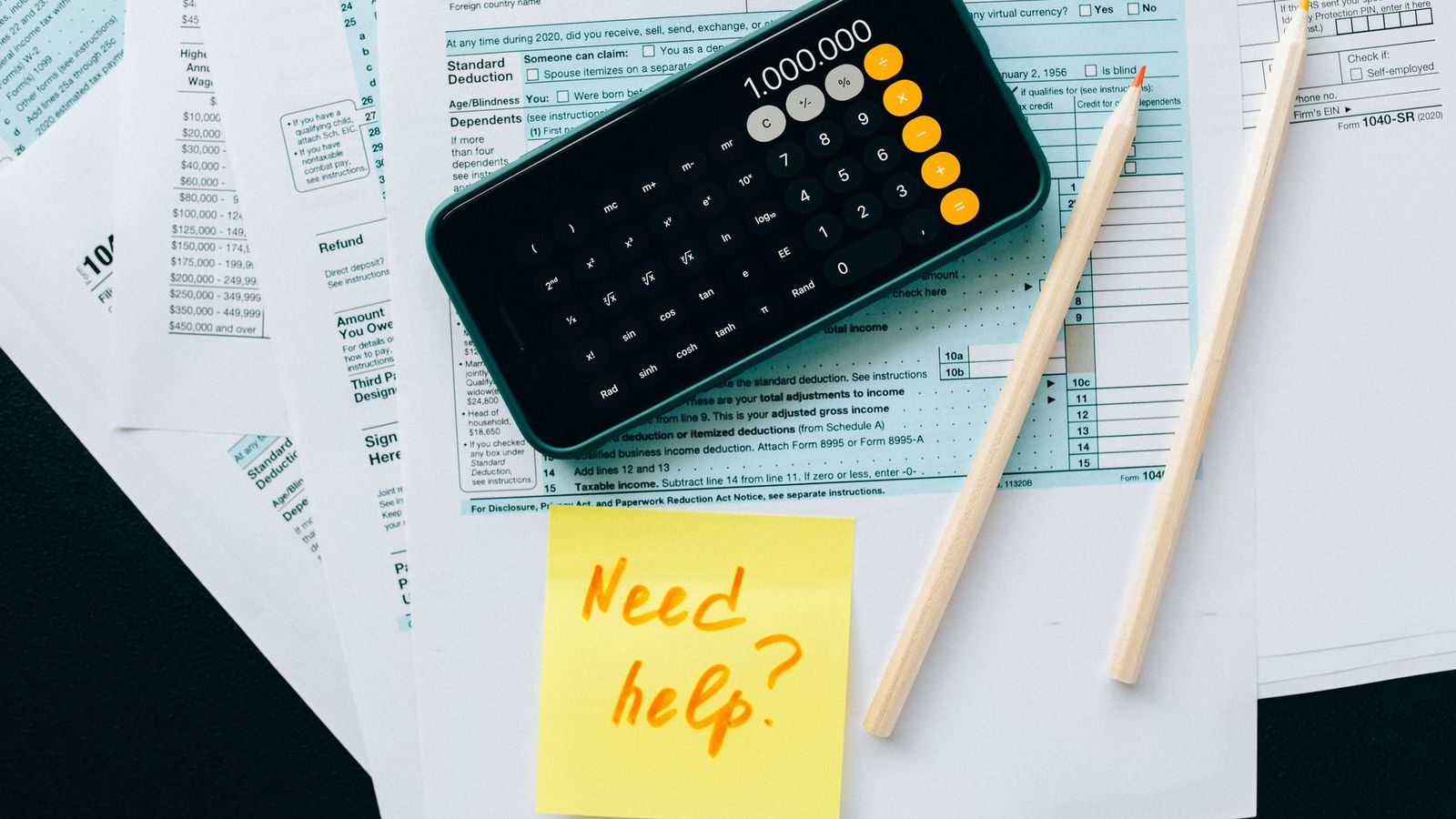 Des documents financiers, une calculatrice et un mot demandant de l'aide