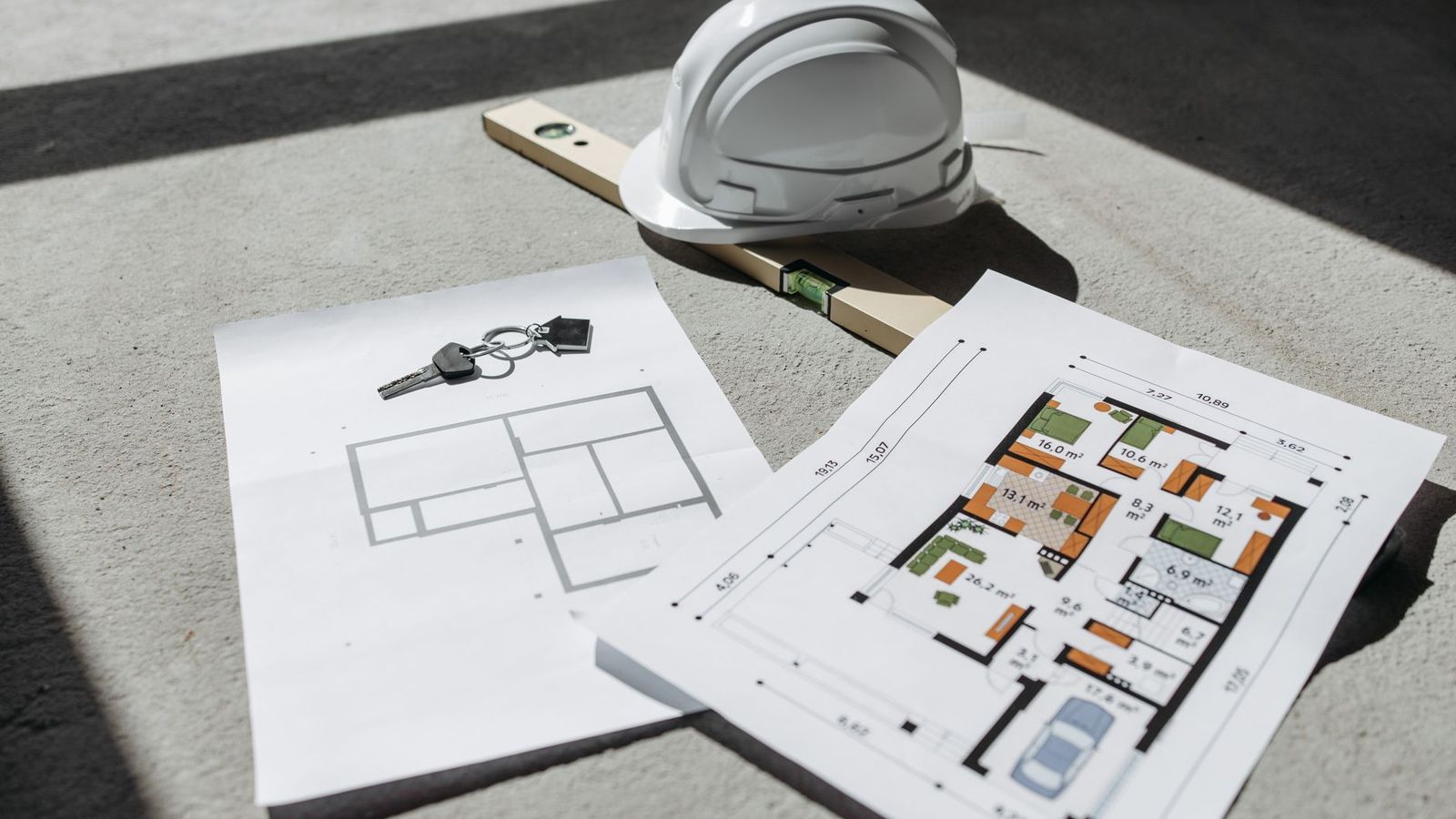Des plans d'architecte, un casque et des clés posés au sol